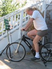 Ed Begley Jr pedaling a bike mounted in a trainer stand outside his home