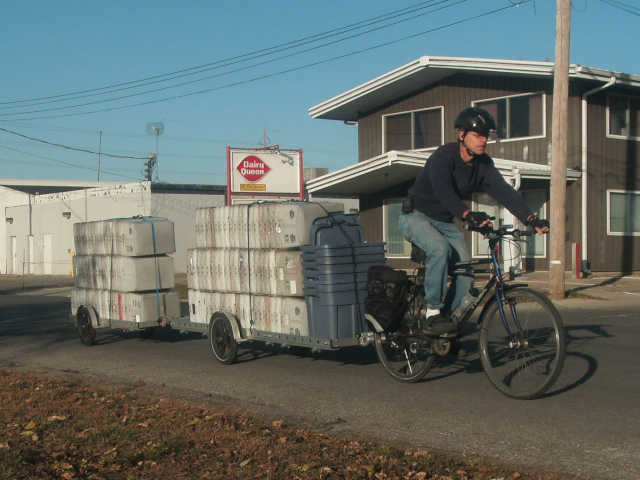 bicycle pulling two long trailers loaded with two stacks of plastic mailtubs