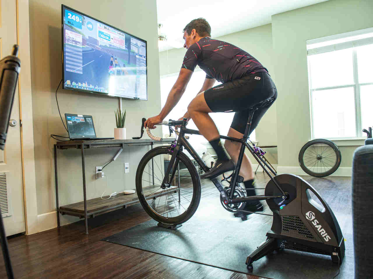 man riding a bike on a trainer while watching TV